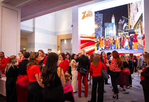 Crowded room of women in red attire with a projection of the Chicago skyline on the wall.